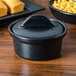 A black ceramic Hall China round casserole dish with a lid and macaroni and cheese inside.