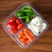 A Fabri-Kal plastic deli container filled with baby carrots and tomatoes.