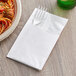 A fork and knife in a white ReadyNap pocket fold dinner napkin.