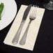 A knife and fork on a white Lavex Linen-Feel Elite guest towel.