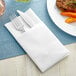 A Touchstone by Choice white linen-feel dinner napkin folded with a fork and knife inside.