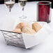 A basket of Lavex white guest towels with rolls on a table.