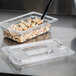 A Carlisle clear plastic lid with a spoon notch on a plastic food container.