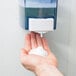 A person's hand with Noble Chemical Novo foaming hand sanitizer from a soap dispenser.