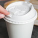 A person's finger using the reclosable tab on a white Dart Optima lid to open a paper cup.