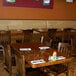 An American Tables & Seating walnut rectangular table top on a wooden table with napkins and a fork and knife.