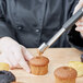A person using a Victorinox apple corer to core a pastry.