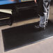 A person standing on a black Cactus Mat anti-fatigue mat.