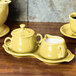 A yellow Fiesta sugar and creamer tray set on a wooden surface.