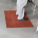 A person standing on a red Cactus Mat VIP Lite anti-fatigue floor mat.