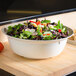 A Thunder Group Jazz melamine bowl with a crackle-finished border filled with salad, mushrooms, and vegetables on a counter.