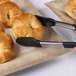 A pair of tongs holding pastries over a Thunder Group Jazz melamine plate with a crackle-finished border.