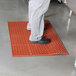 A person standing on a red Cactus Mat rubber floor mat.
