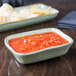 A Tuxton Artisan Sagebrush rectangular side dish filled with red sauce next to a bowl of chips.