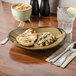 A Tuxton Mojave China plate with grilled chicken on a table.