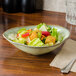 A Tuxton TuxTrendz Sagebrush Capistrano bowl filled with salad on a wood table.
