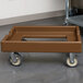A brown plastic Cambro Camdolly with wheels.