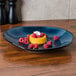 A Tuxton TuxTrendz Artisan Night Sky china ellipse plate with raspberries and cream on it.