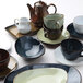 A group of Tuxton Artisan Sagebrush china cups on a table.