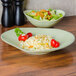 A TuxTrendz Artisan Sagebrush china plate with rice and salad on a table.