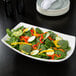An American Metalcraft oval stoneware serving bowl filled with salad on a table.