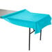A table with a Bermuda Blue Creative Converting plastic table cover on it.