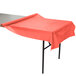 A table with a coral orange Creative Converting plastic table cover on it.