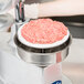 A Globe Patty Press with raw meat in a pink container.