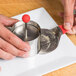 A person using an Ateco round metal mold to make a cake.