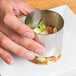 A person's hand holding a small metal bowl of food.