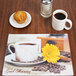 A table set with a Hoffmaster Good Morning Paper Placemat, a cup of coffee, and a muffin.