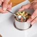 A person's hands using Ateco round ring molds to shape food in a bowl.
