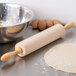 A maple Ateco rolling pin and dough on a table.