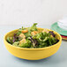 A yellow Fiesta china bistro bowl filled with salad and croutons.