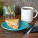 A Fiesta turquoise china appetizer plate with a slice of apple pie on it, on a table with a white mug filled with brown liquid.