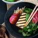 A bowl of Kikkoman Tamari soy sauce on a plate of Asian food with chopsticks.
