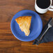 A piece of pie on a Fiesta® Lapis blue China appetizer plate next to a cup of coffee on a table.