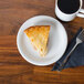 A slice of pie on a Fiesta® White China appetizer plate next to a cup of coffee.