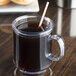 A clear Tritan mug filled with coffee and a straw.