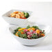 Two Tuxton porcelain bowls filled with salad, shrimp, and vegetables.