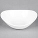 A Tuxton porcelain white Capistrano bowl on a grey surface.