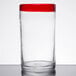 A clear Libbey cooler glass with a red rim on a table.