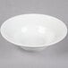 A Tuxton bright white china soup bowl with an embossed white rim on a white surface.