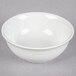 A Tuxton bright white China nappie bowl with an embossed rim on a gray surface.