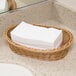 A basket of Lavex Linen-Feel white paper guest towels.