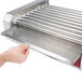A hand holding a Grand Slam metal replacement drip tray under a hot dog roller.