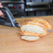 A Waring bread knife cutting a loaf of bread on a cutting board.