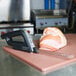 A Waring electric knife cutting a piece of meat on a cutting board.