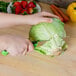 A person using a Mercer Culinary Millennia Colors produce knife to cut a cabbage.