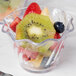 A clear plastic Cambro swirl bowl filled with sliced fruit.